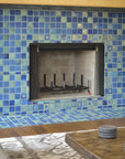 A close up shot of a blue iridescent tiled fireplace. The details in the accent tiles are more visible surrounding the fireplace's opening.