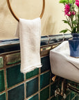 Detail shot of the blue, green, and "Aurora" iridescent 4x4 field tiles and custom trim. There is a Pewabic Petite Vase in view on the sink in our dark-blue "Midnight" glaze. The vase is holding bright green and pink flowers.
