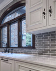 White quartz countertops with ornate white cabinets showcase the pale gray of the subway tiles. 