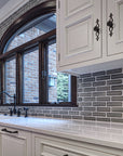 White quartz countertops with ornate white cabinets showcase the pale gray of the subway tiles.