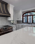 The entire kitchens boasts the bright whites of the counters and cabinets with the sleek gray tiles bahind.