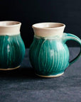 This mug features the matte turquoise Pewabic Blue glaze. The lip of the mug is cream colored.