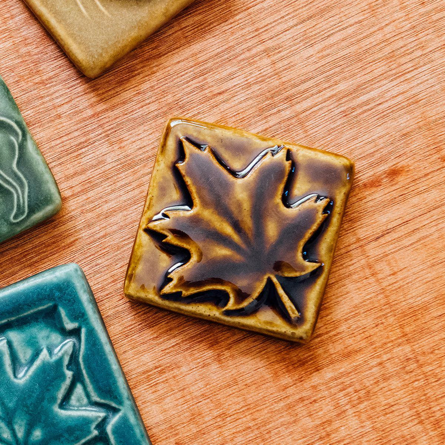 The molasses glazed maple leaf tile is featured. This tile is a deep glossy brown.