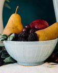This classic bowl holds colorful fruit - two pears, blackberries and a peach. The bowl features the glossy pale blue-gray Frost glaze.