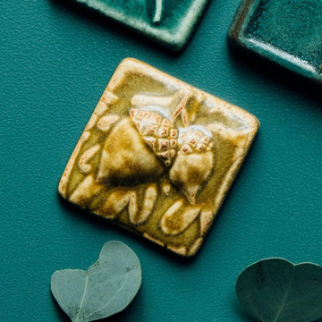 The ceramic acorn tile has an embossed image of two acorns hanging together with oak leaves in the background.