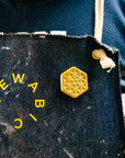 The small hexagonal Hex Pin features a line design of many interconnected triangles. The center has a tiny hexagon with a six-sided starburst emanating into the triangles. This pin features the the gold metallic Blush Iridescent glaze.