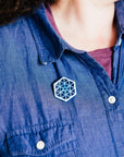 The small hexagonal Hex Pin features a line design of many interconnected triangles. The center has a tiny hexagon with a six-sided starburst emanating into the triangles.