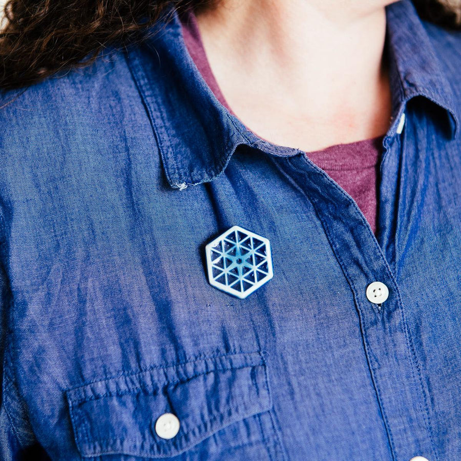 The small hexagonal Hex Pin features a line design of many interconnected triangles. The center has a tiny hexagon with a six-sided starburst emanating into the triangles.