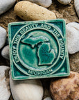 The 4x4 ceramic Michigan tile includes an embossed image of the two peninsulas of Michigan. Encircling these shapes are the words "Enjoy the Beauty and the Bounty, Michigan". This Beauty and Bounty of Michigan tile is featured in the matte Pewabic green glaze.