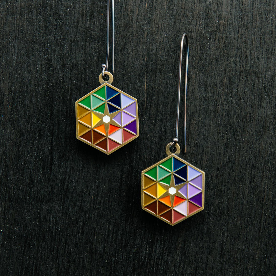 The Hex Earrings with a brushed bronze hex featuring the bright colored triangles on silver loops.