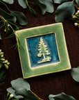 The Pine Tree Tile features a 3D outline of a pine tree inside of a thick, smooth square border.