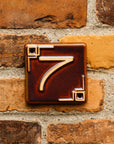 The Craftsman style ceramic 7 address number is in the satin reddish brown Carmine glaze option.