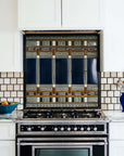 The Wright Backsplash features an intricate geometric design harkening to Frank Lloyd Wright's mid-century design. The tiles feature multiple blue shades with details in grays, browns and white.