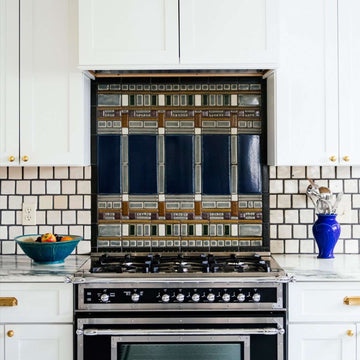 The Wright Backsplash features an intricate geometric design harkening to Frank Lloyd Wright's mid-century design. The tiles feature multiple blue shades with details in grays, browns and white. 