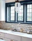 The rest of the Pewabic tile backsplash are pale shades of white with dark blueish grout.