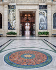 The Rivera Court boasts light intricately carves stone walls and larger-than-life murals, but we are focused on another art piece. The Pewabic tile floor mural features a circular mosaic pattern of blues, greens and rust colors. A star pattern bursts from the center with many points.