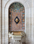 In the center of the drinking fountain is the golden head of a child in Aztec design. 