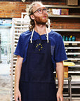 Shown on a Pewabic artisan in the kiln room of Pewabic, this apron has a solid rope around the back of the neck of the wearer.