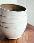 A stack of bowls feature the creamy white Birch glaze that has some natural brown speckling.