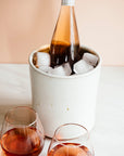 Another application of this functional vessel, this Crock is filled with ice and holds a bottle of rosé. Two stemless wine glasses hold more of the pale pink drink.