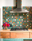 Multicolored tile backsplash in a kitchen with modern cabinets and a jade green countertop
