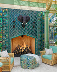 Horizontal, wide shot of the custom fireplace surrounded by topical plants, palms, and wicker furniture set.