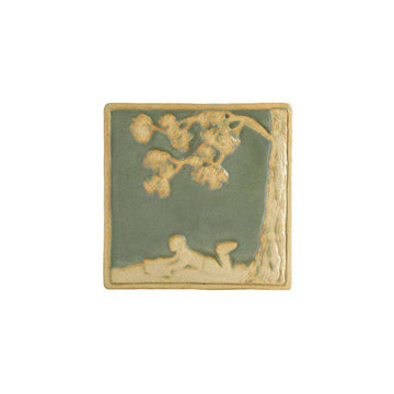 This ceramic Boy Reading Tile features the design of a child laying under a tree while reading a book. The background color is a pale green glaze with a satin finish while the raised design has been scraped down to the clay.