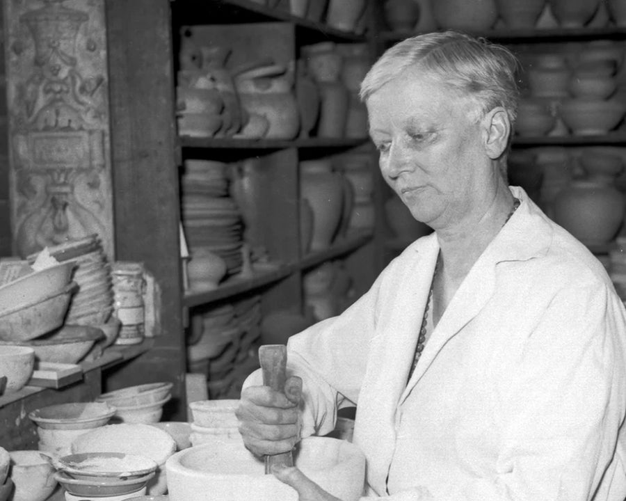 Mary Chase Perry Stratton using a mortar and pestle to mix glaze ingredients.