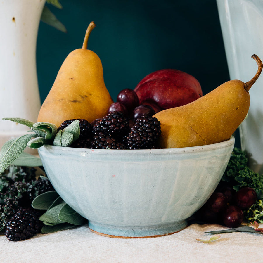 This classic bowl holds colorful fruit - two pears, blackberries and a peach. The bowl features the glossy pale blue-gray Frost glaze.