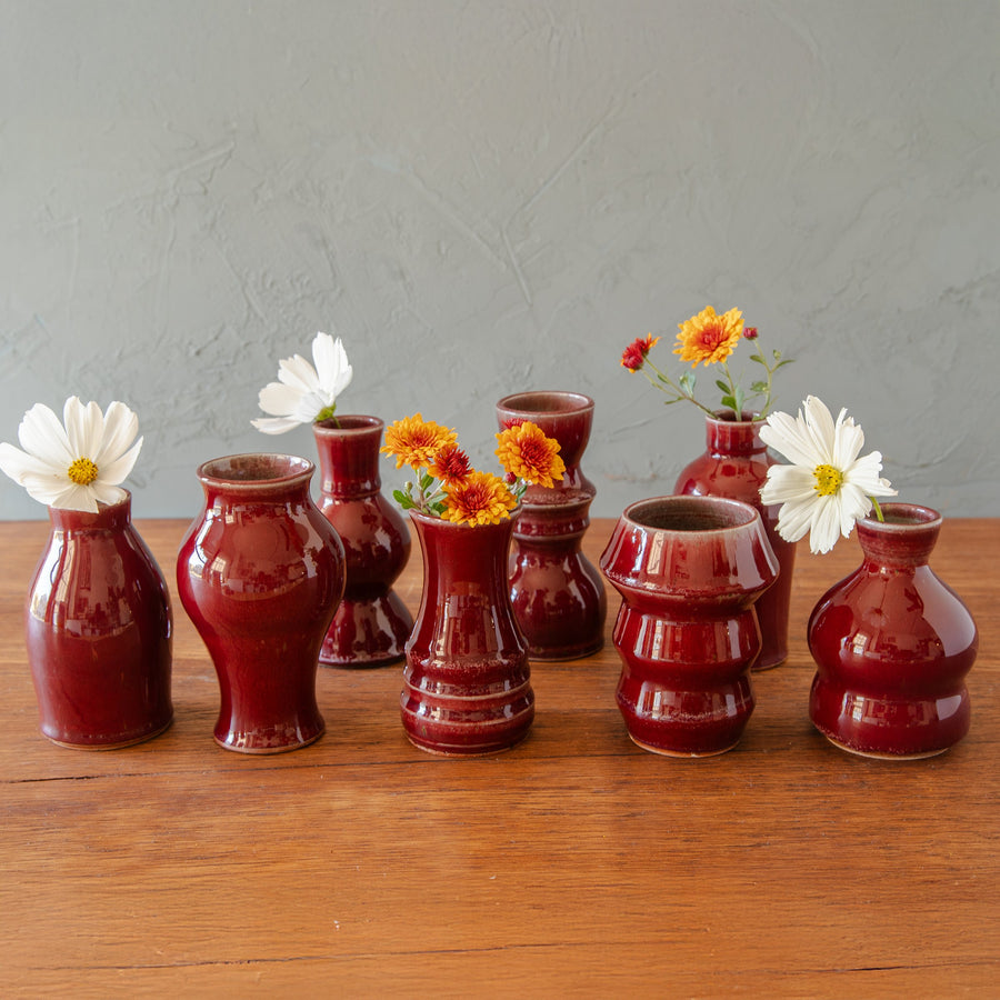 A grouping of six Petite Vases in Copper Iridescent glaze. The vases range from having a penny-like appearance, to a cascading sunset.