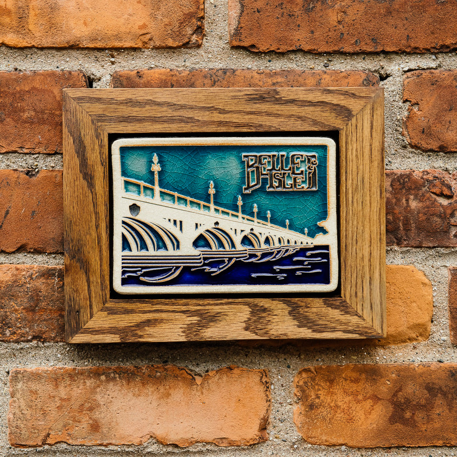 The framed Belle Isle Tile hangs on a red brick wall.