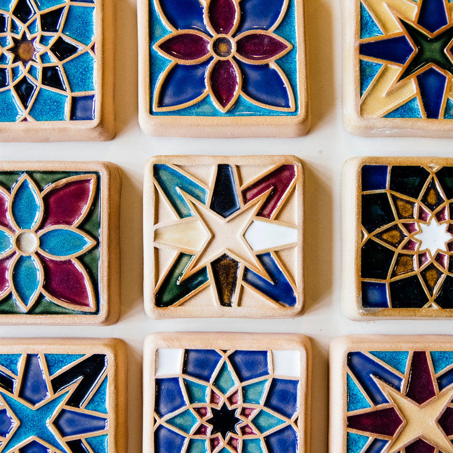 Nine hand-painted tiles feature geometric designs and multicolored glazes.