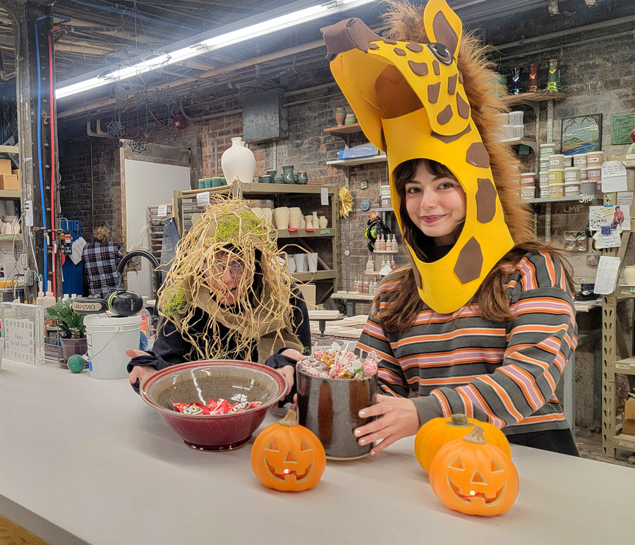Two people in a workshop setting with Halloween decorations and props.