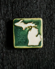This hand painted tile has a dark matte green background with bright white peninsulas.