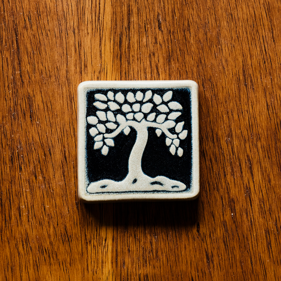 This ceramic black/white Botanical Tree tile features a white tree and border on a black background.