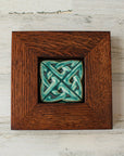 The 3 inch square Eternity Knot Tile includes the design of two oval shapes intertwined to create the Celtic Eternity knot. This tile features the matte turquoise Pewabic Blue glaze which beautifully offsets the deep reddish brown oak wood frame.
