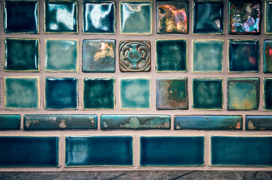 A detail of a Pewabic tile backsplash features square blue tiles including iridescent, glossy, and matte finishes.