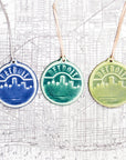 The Detroit ornaments feature the Detroit skyline with the Renaissance Center in the middle. The word "Detroit" is carved along the top of the circular tile in an Olde English font similar to the one used for the Detroit Tigers' logo. All three color options are represented in this image.