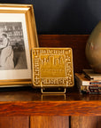 Decorative Old Detroit tiles in glossy Honey glaze on a handcrafted Stickley cabinet  next to a stack of books and framed photo. 