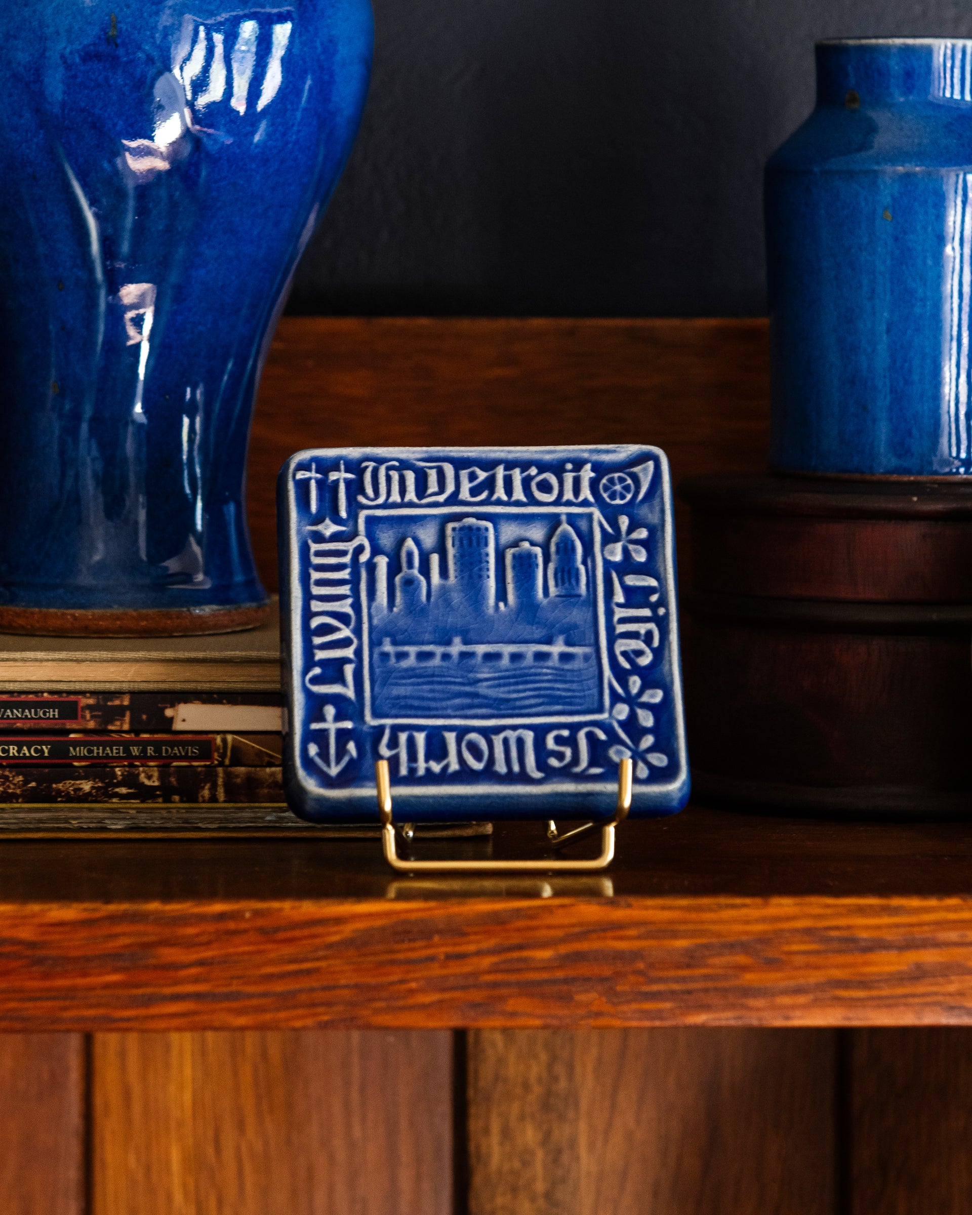 Decorative Old Detroit tiles in glossy Lake Superior glaze on a handcrafted Stickley cabinet next to two vases in bright-blue Ultramarine. 