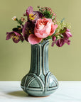 Glossy, green, Balsam Vase with a vibrant bouquet set on white marble with a light green background. 