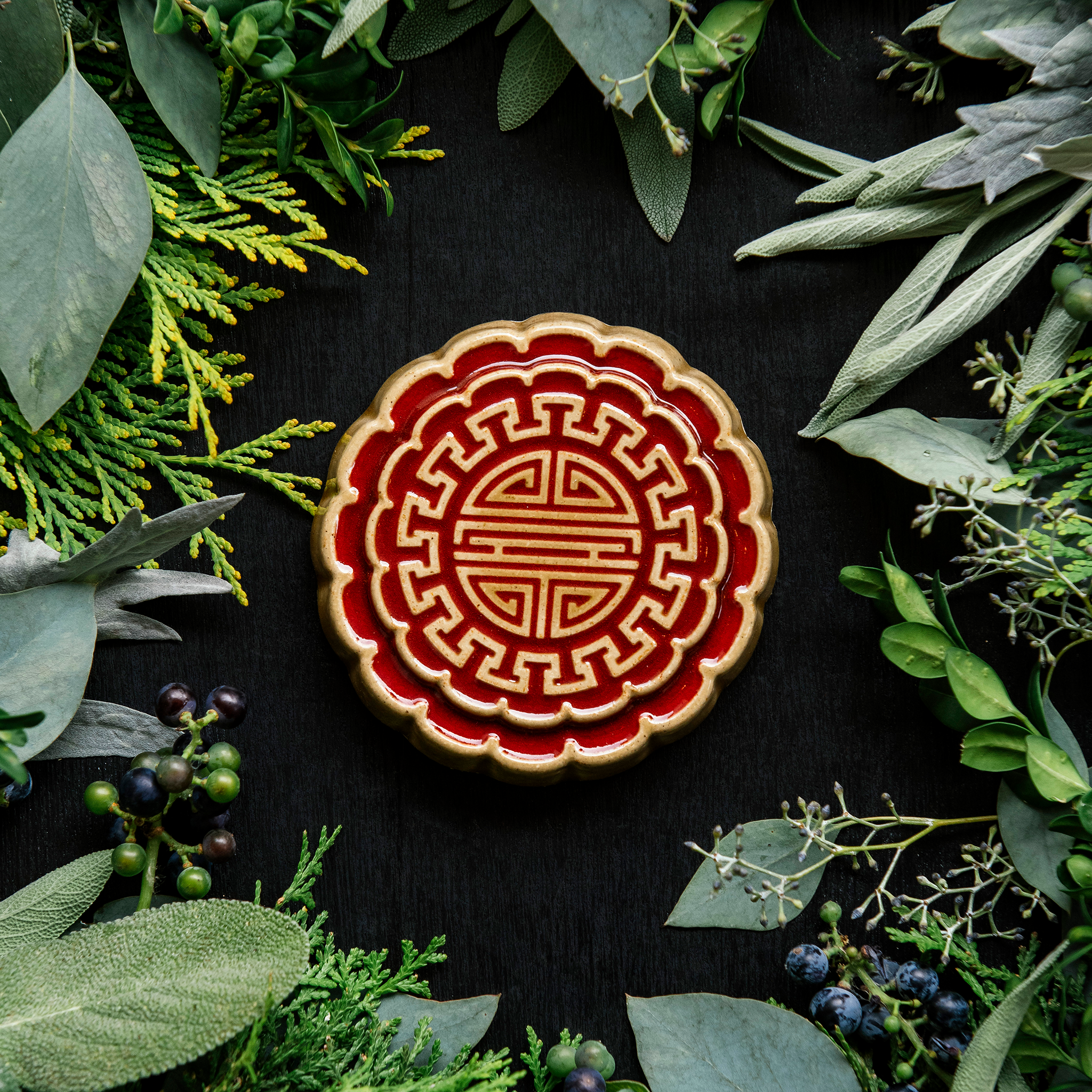 A Mooncake Paperweight in two-tone Scarlet/Honey surrounded by cool greenery and delicate concord grapes.