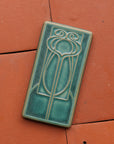 This vertical rectangle tile has an abstract low relief design. Interconnecting hard and curved lines come together to create a craftsman style motif.