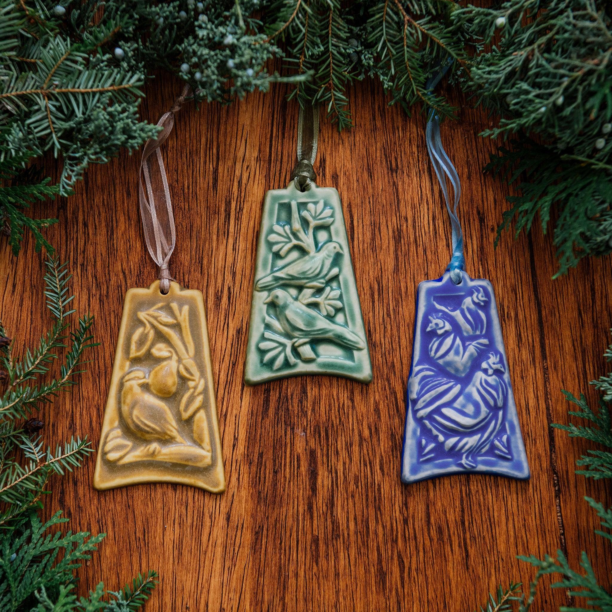 Three ornaments are against a white background. One has an image of a partridge sitting on a branch with a pear in the background, one shows two turtle doves resting on a tree branch and the last has three chickens in a row, each getting smaller as they are further from the viewer.