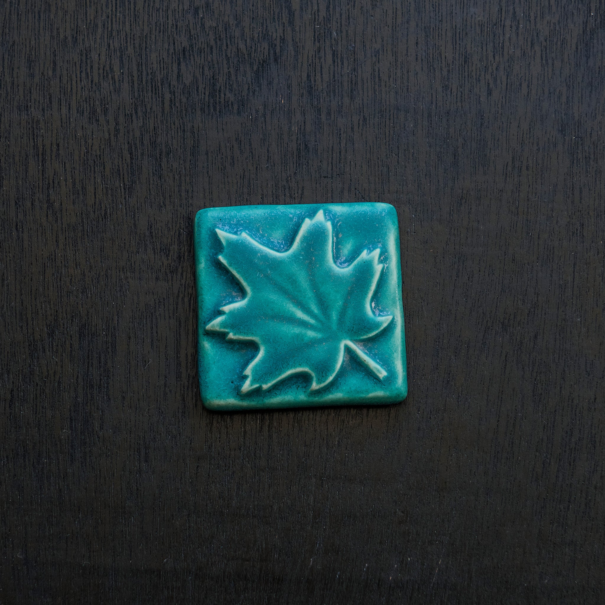 The Pewabic blue glazed maple leaf tile is featured. This tile is a matte turquoise blue.