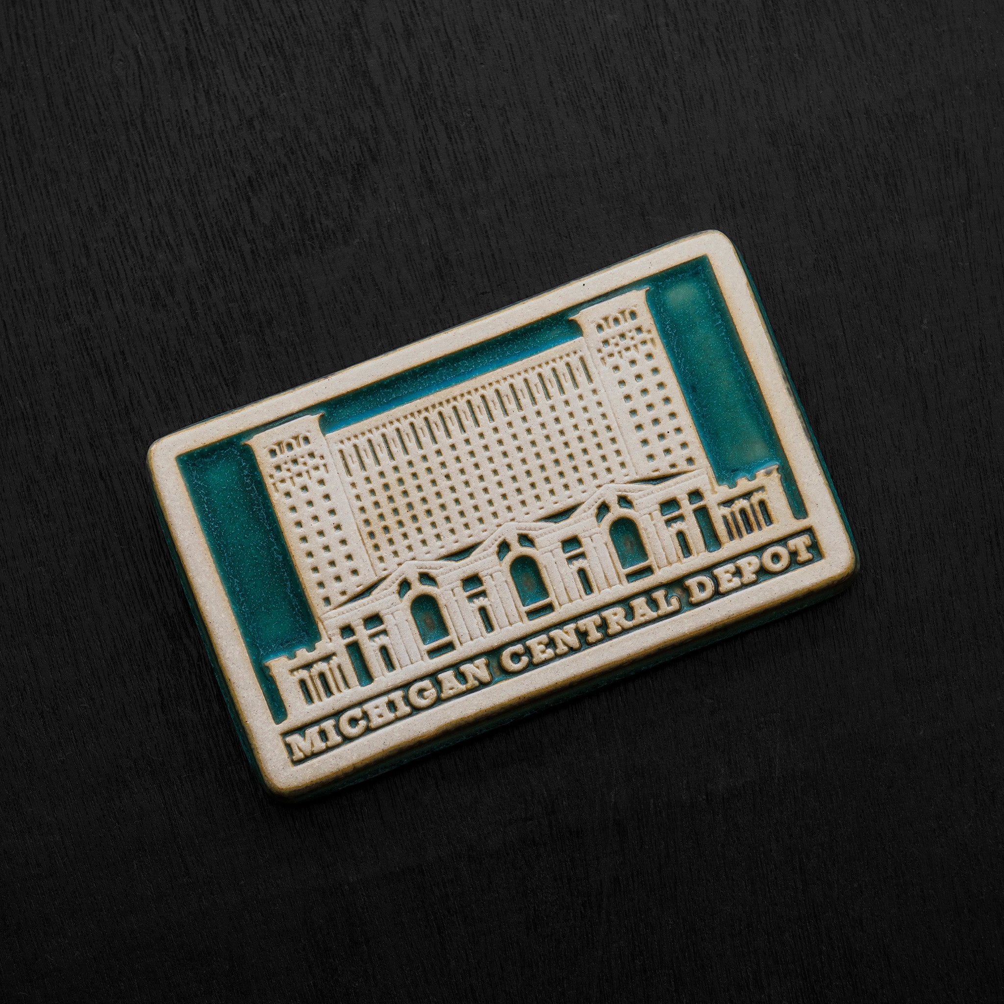 The two toned nature of the tile means that the design and words have been scraped of their glaze giving them a creamy off-white look while the background of the image is in the crystalline, shimmering deep green Viridian glaze.