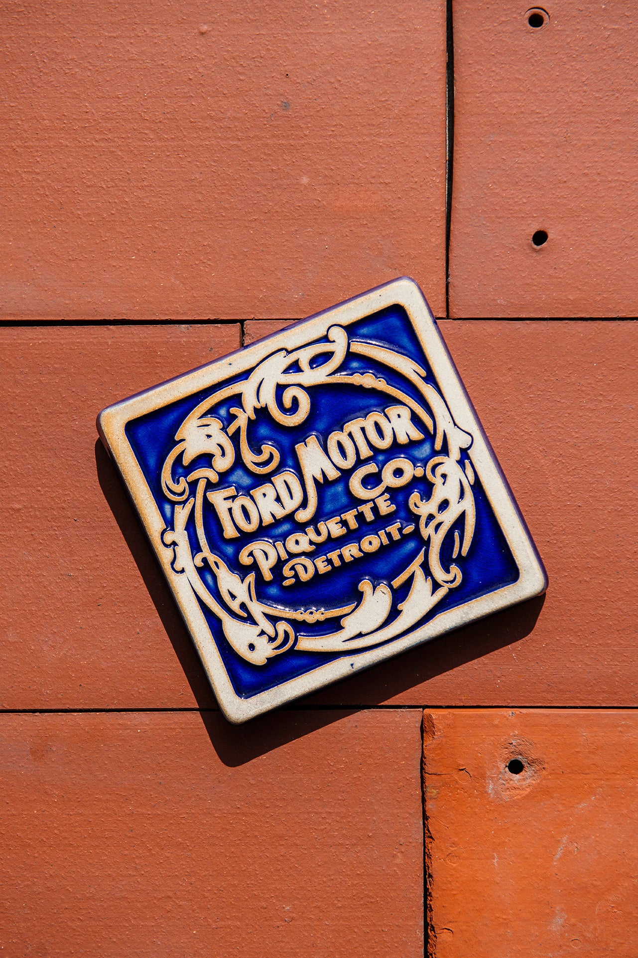 Ford Motor Co. Piquette logo tile on a terra cotta roof tile background.