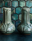 Two green Balsam Celtic Vases against an Iridescent fishscale tile background. 