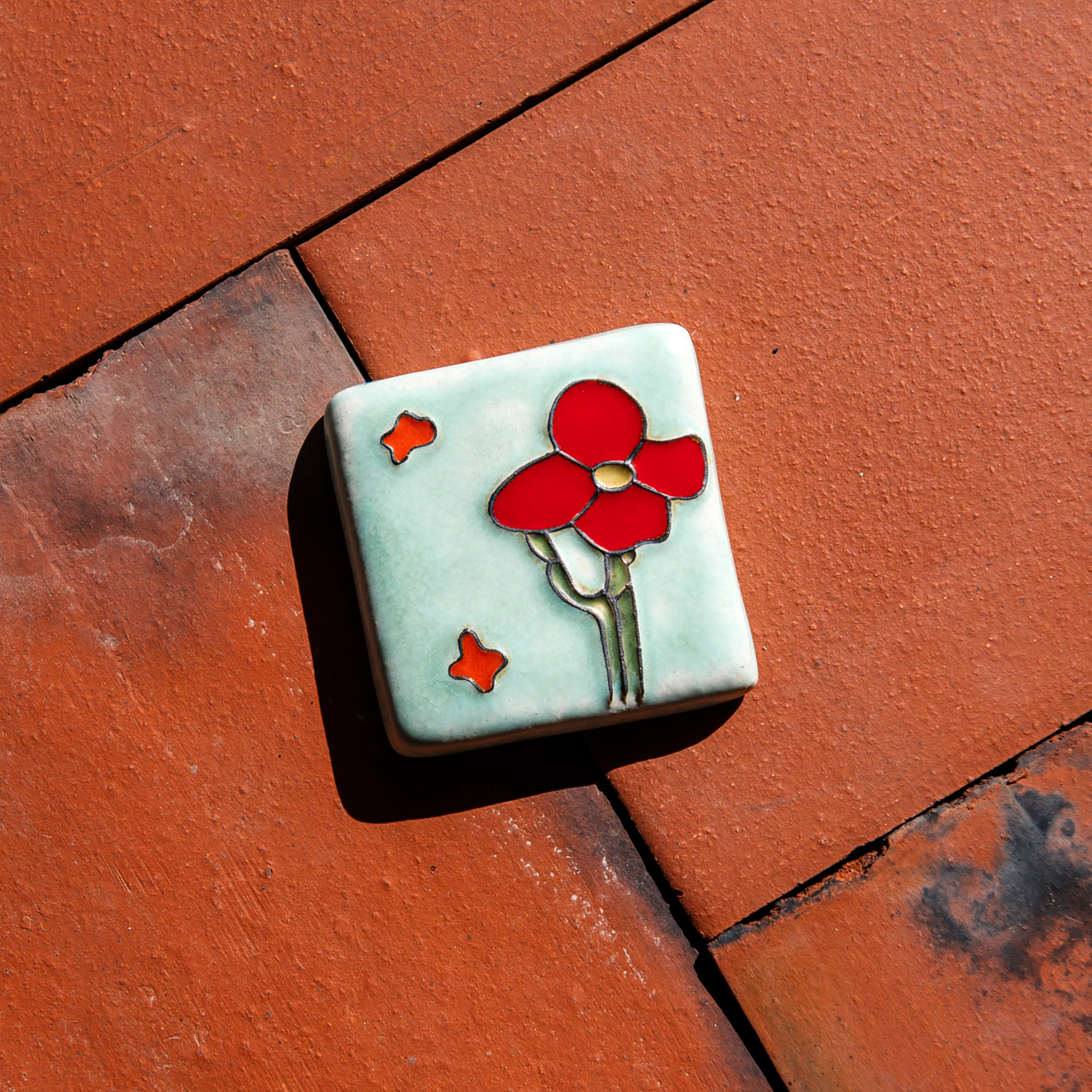 The Cactus Flower Tile features a large, four petalled flower on a thicker cactus stem. Two small petals seem to fly in the wind next to it.