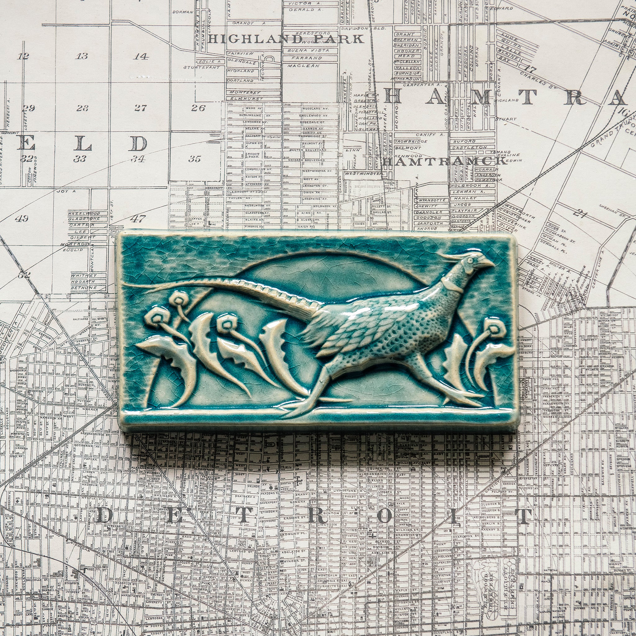 This hand-sculpted tile features a pheasant running through a field of dandelions. It is featured in a glossy blue Glacier glaze. 